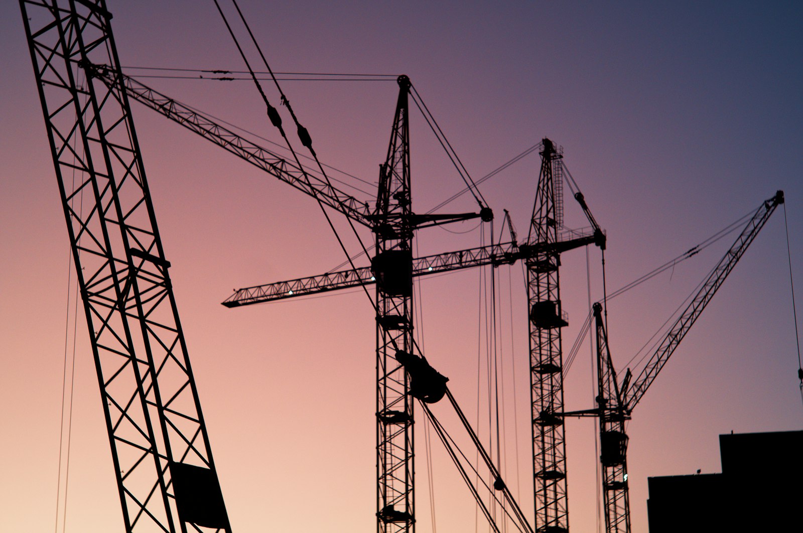 Tower crane silhouettes over a construction site at dusk