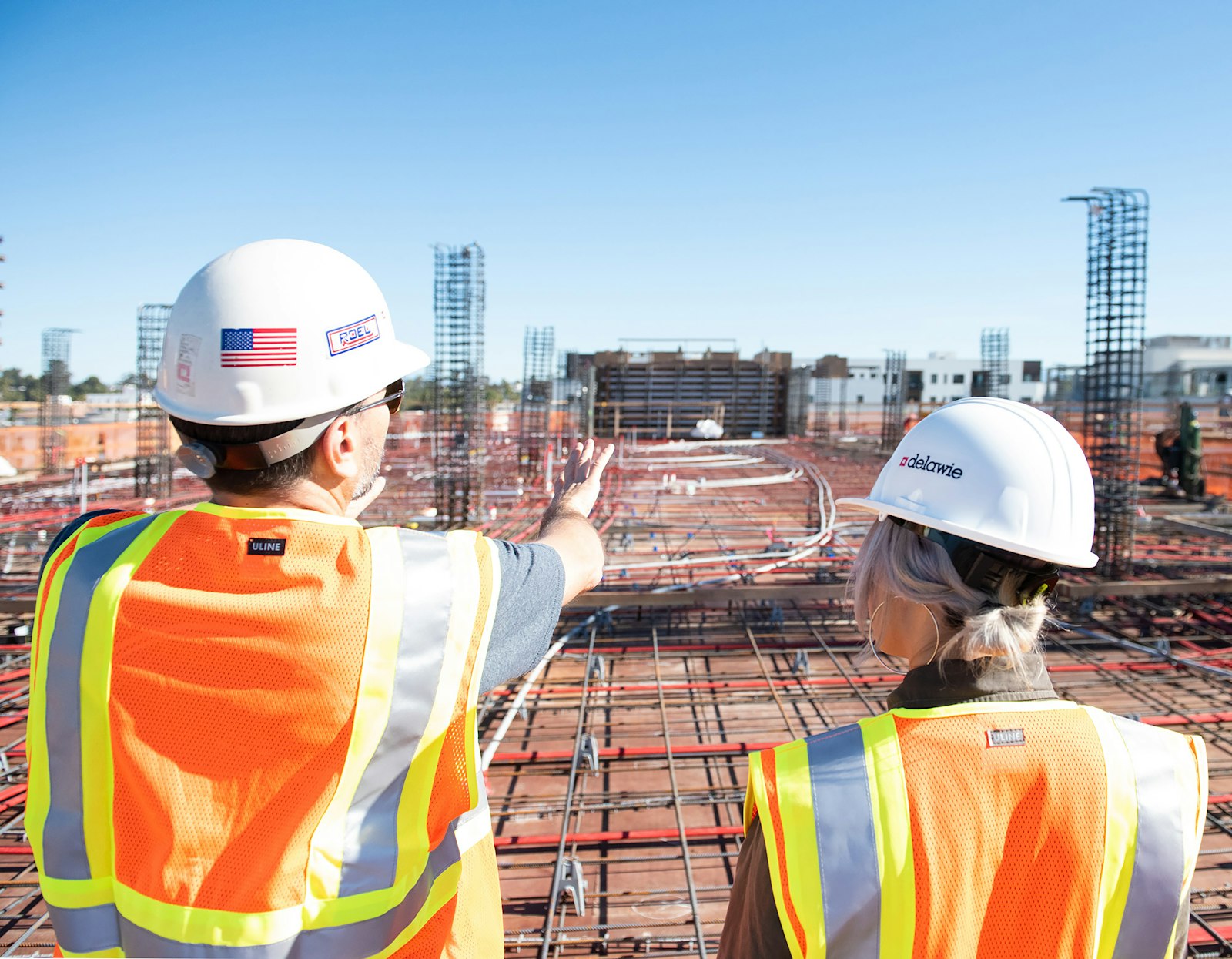 Two engineers in hard hats reviewing progress on a construction site
